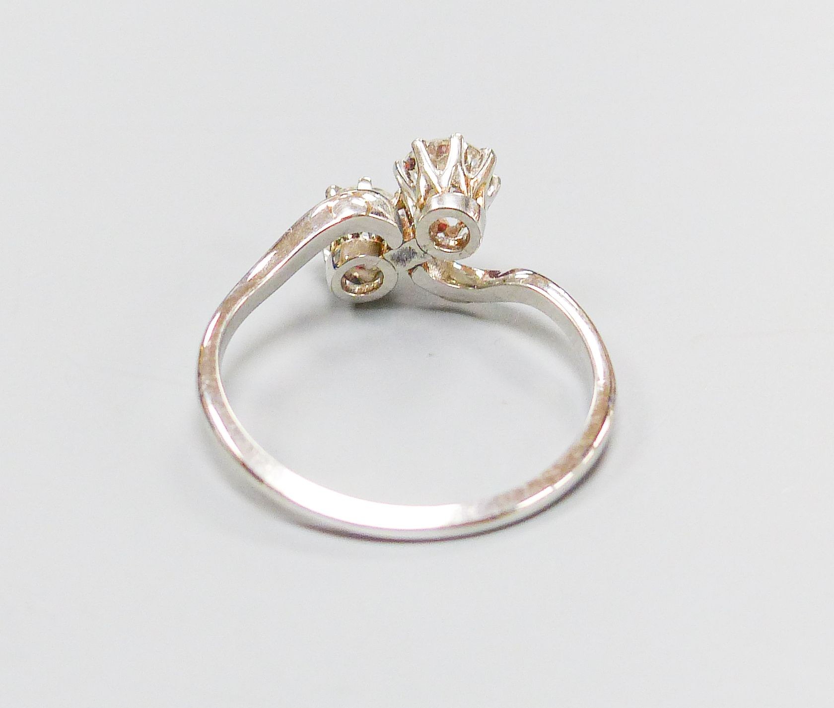 A white metal and two stone diamond set crossover ring, size K, gross 2.4 grams